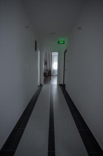 an empty hallway with white walls and a green exit sign at Hany Sweet in Niš