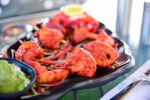 a black plate of food with shrimp and coleslaw at Hotel Casa by the lake in Udaipur
