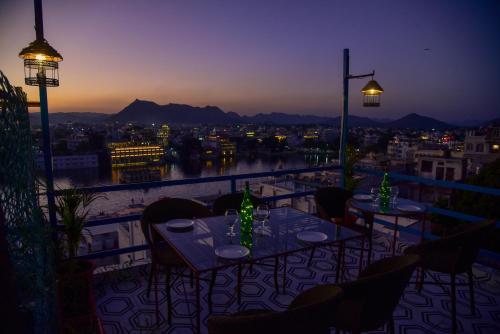 a balcony with tables and chairs and a view of the city at Hotel Casa by the lake in Udaipur