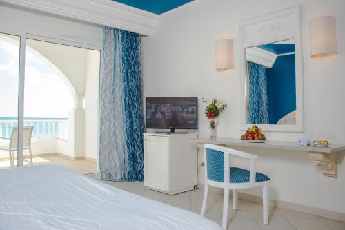 a bedroom with a bed and a television and a table at Cap Bon Kelibia Beach Hotel & Spa in Kelibia