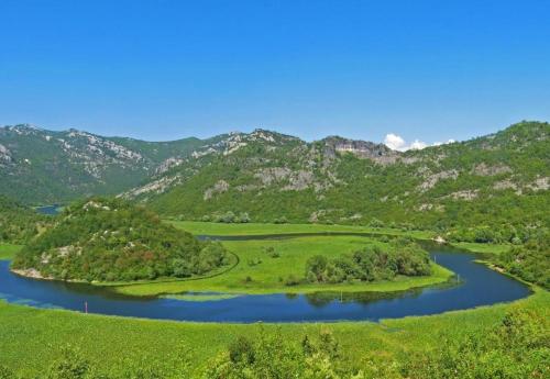 an island in a river with mountains in the background at Holiday Home Pavle in Rijeka Crnojevića
