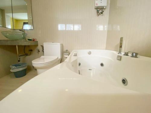 a white bathroom with a tub and a toilet at ฮักเคียงโขง HUG Khieng Khong Nongkhai Hostel in Nong Khai