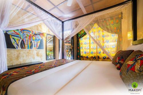a bed in a room with a painting on the wall at Makofi Guest House in Nungwi