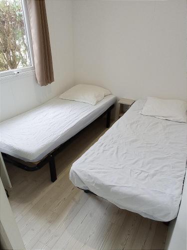 deux lits dans une petite pièce avec une fenêtre dans l'établissement camping 4 étoiles le lac des rêves, à Pérols