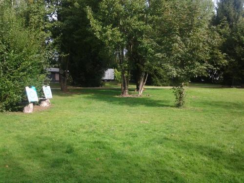 two signs in a field with trees and grass at Camping Le Canoë in Chaussin
