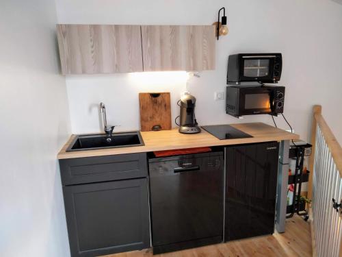une petite cuisine avec un évier et un micro-ondes dans l'établissement Gîte de charme au coeur de Ruoms avec terrasse, à Ruoms