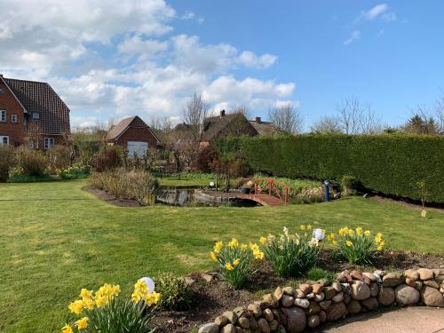 a garden with a bridge and flowers in a yard at Haus Daheim in Utersum