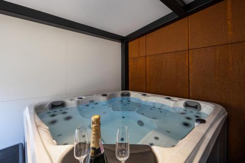 a jacuzzi tub with two glasses and wine bottles at Zerm Holiday House with jacuzzi and sauna - Gorski kotar in Mrkopalj