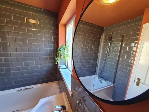 a bathroom with a tub and a sink and a mirror at RARE FIND 3BR Detached with Garage Bike Park Wales & Brecon Beacons in Merthyr Tydfil