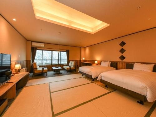 een grote slaapkamer met 2 bedden en een televisie bij Kutsurogijuku Chiyotaki in Aizuwakamatsu