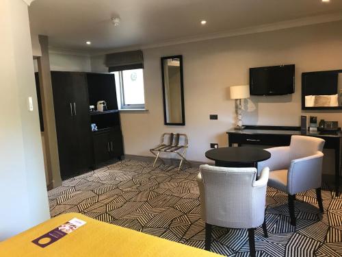 a hotel room with a table and chairs and a desk at Hunton Park Hotel in Kings Langley