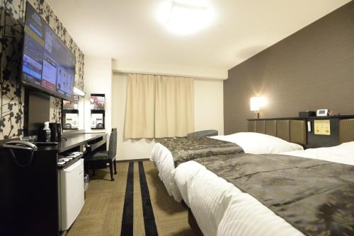 a hotel room with two beds and a flat screen tv at APA Hotel Muroran in Muroran