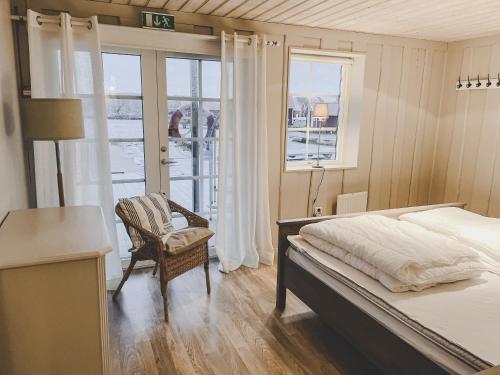 a bedroom with a bed and a chair and a window at Havets Magasin in Väjern