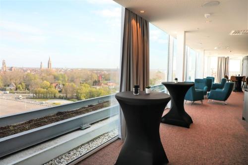 a room with tables and chairs and a large window at Radisson Blu Hotel, Bruges in Bruges