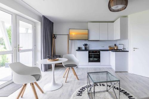 a white living room with a table and chairs at Haus Seeblick Wohnung 04 in Wohlenberg