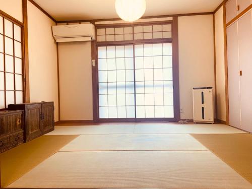 Yokohama HY House في يوكوهاما: غرفة فارغة بنوافذ كبيرة وباب كبير