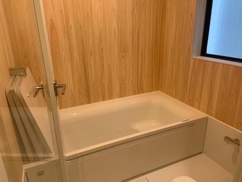 y baño con bañera blanca y paredes de madera. en Yokohama HY House en Yokohama