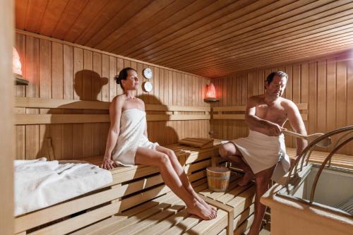 a man and a woman sitting in a sauna at Hotel Gänsleit in Söll