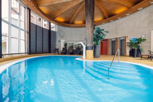 a large swimming pool in a building with a wooden ceiling at Hotel Bon Alpina in Innsbruck