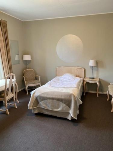 a bedroom with a bed and two chairs and a mirror at Bruksmässen Hotell in Degerfors