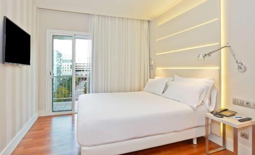 - un lit blanc dans une chambre avec fenêtre dans l'établissement NH Barcelona Les Corts, à Barcelone