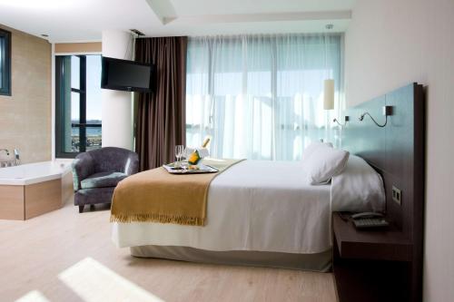 a hotel room with a large bed and a bath tub at NH Gijón in Gijón