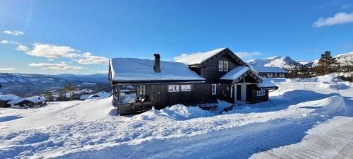 a house covered in snow in the mountains at Wonderful cabin with amazing mountain - view in Lifjell
