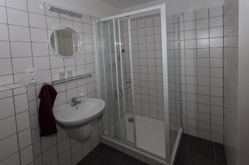 a white bathroom with a sink and a shower at Penzion Živec - restaurace a ubytování in Písek