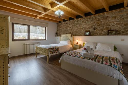 a bedroom with two beds and a stone wall at Casa D'Augusta - Agroturismo in Miranda do Douro