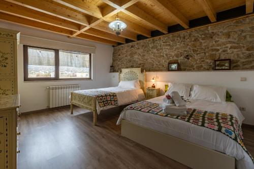 una camera da letto con due letti e un muro di pietra di Casa D'Augusta - Agroturismo a Miranda do Douro