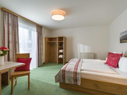 a bedroom with a bed and a table and a window at Hotel Gänsleit in Söll