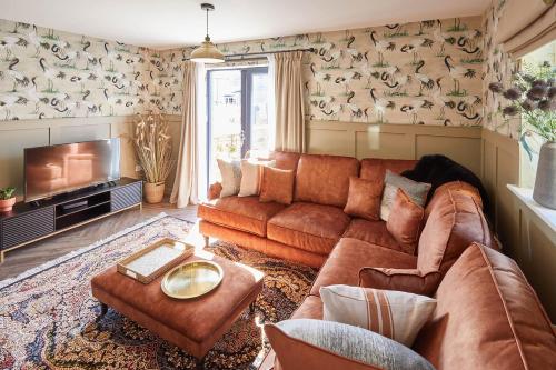 a living room with a brown couch and a tv at Host & Stay - Fox Cottage in Bellingham