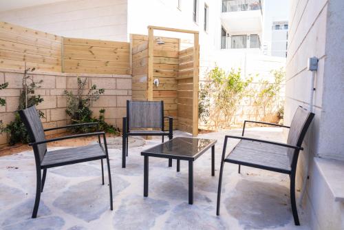 Splendid Achziv Garden Apartment by Sea N' Rent في نهاريا: ثلاثة كراسي وطاولة على الفناء
