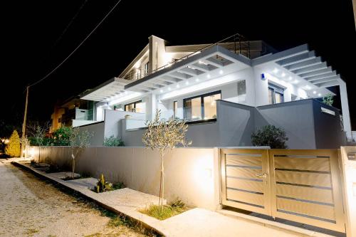 una casa blanca con una puerta y una valla en Filos Suites, en Nea Iraklitsa