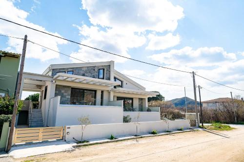 a house with a white fence in front of it at Filos Suites in Iraklitsa