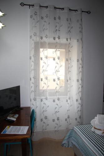 a window with a white curtain with a flower pattern at B&B IlGirasole in Paravati