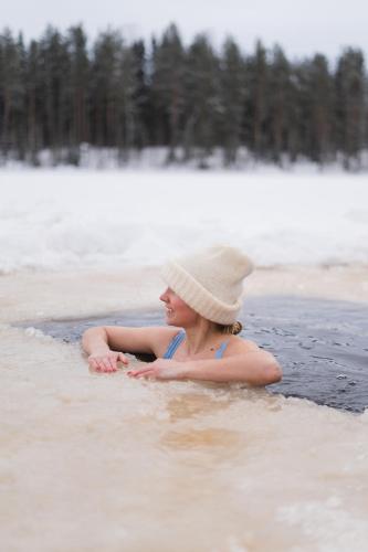 a woman in a hat sitting in the water at Holiday Village Tahko-Tours in Tahkovuori