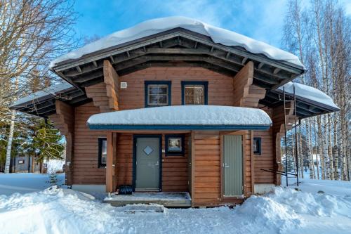 a wooden cabin with a snow covered roof at Holiday Village Tahko-Tours in Tahkovuori