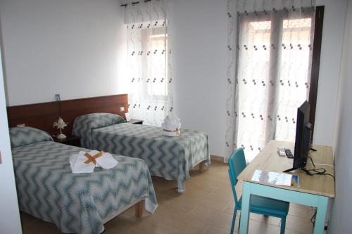 Habitación de hotel con 2 camas, mesa y TV en B&B IlGirasole, en Paravati