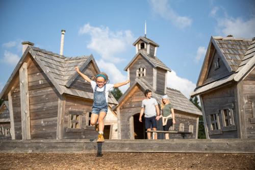 a girl jumping in front of a play house at Hotel Planja in Zreče