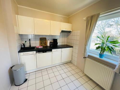 a small kitchen with white cabinets and a window at Strandapartment in Westerland für 2-4 Personen in Westerland (Sylt)