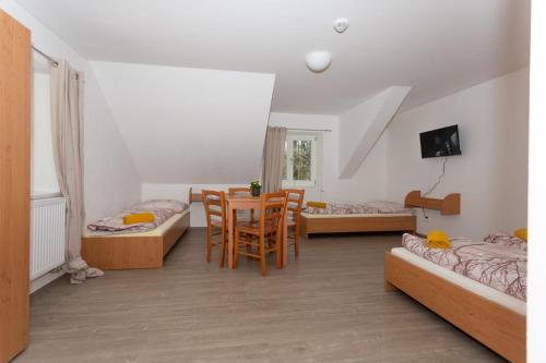 a room with three beds and a table and chairs at Penzion Živec - restaurace a ubytování in Písek