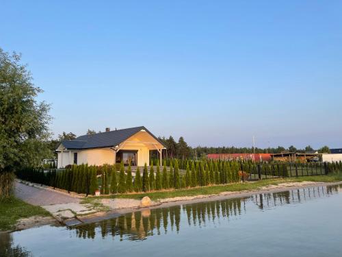 una casa con una valla junto a un cuerpo de agua en Dom nad jeziorem obok Uniejowa en Przykona