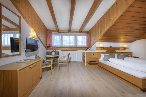 Schlafzimmer mit einem Bett und einem Schreibtisch mit einem TV in der Unterkunft Hotel Wilma in Nals