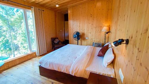 a bedroom with a bed and a large window at THEHIMALAYANLIVING WHISTLING PINES in Mukteswar