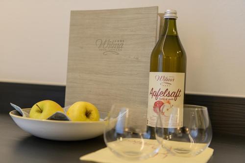 a bottle of wine next to two glasses and a bowl of apples at Hotel Wilma in Nalles