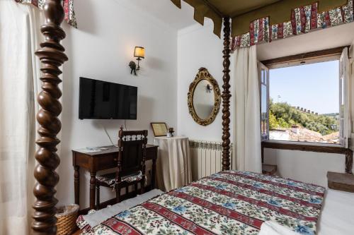 a bedroom with a bed and a desk and a television at Casa de S. Thiago do Castelo in Óbidos