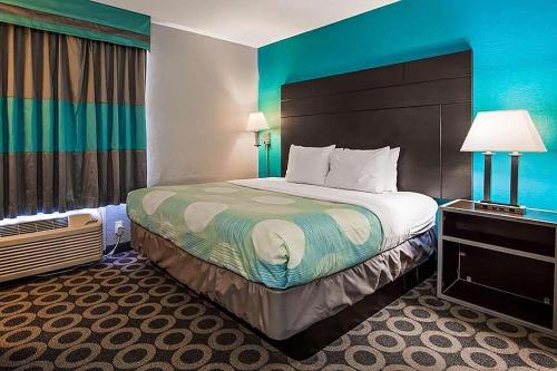 a hotel room with a large bed and a blue wall at Travelodge by Wyndham San Antonio Downtown Northeast in San Antonio