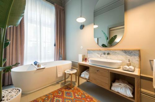 a bathroom with a tub and a sink and a mirror at Jardins do Porto - by Unlock Hotels in Porto