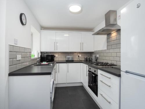 a kitchen with white cabinets and black counter tops at Apex Living NE - Beachville House 4 Beds FREE PARKING in Sunderland